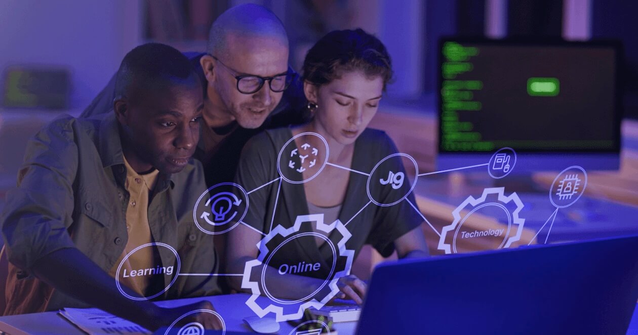 Small team gathered around computer screens with immersive learning icons floating around them